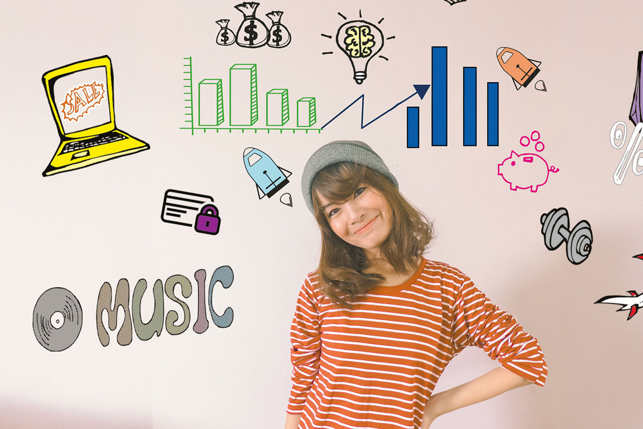 Junges Mädchen mit grauer Beanie-Mütze steht vor einer Wand mit Finanz-Doodles