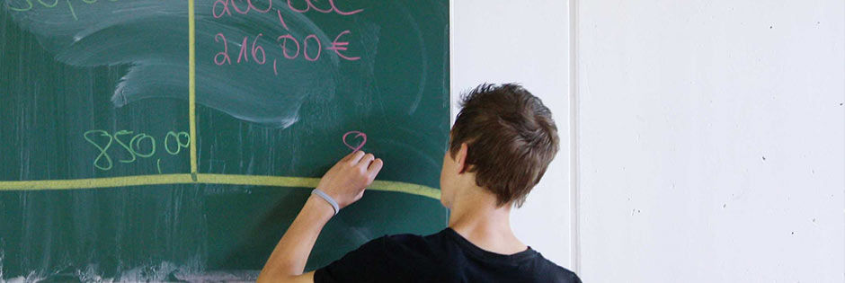  Ein Junge schreibt an einer Tafel