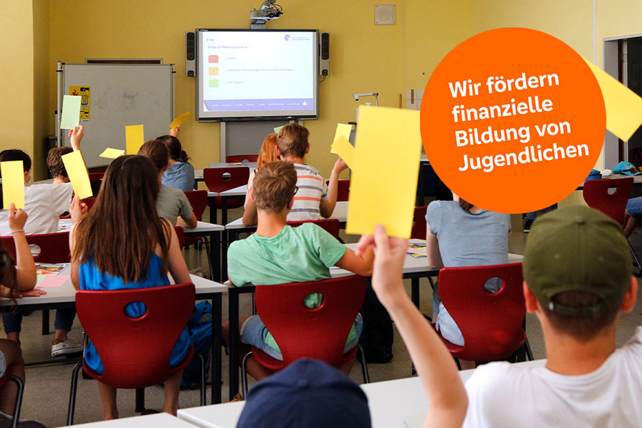 Schulklasse im Unterricht, die Schülerinnen und Schüler heben gelbe Karten hoch