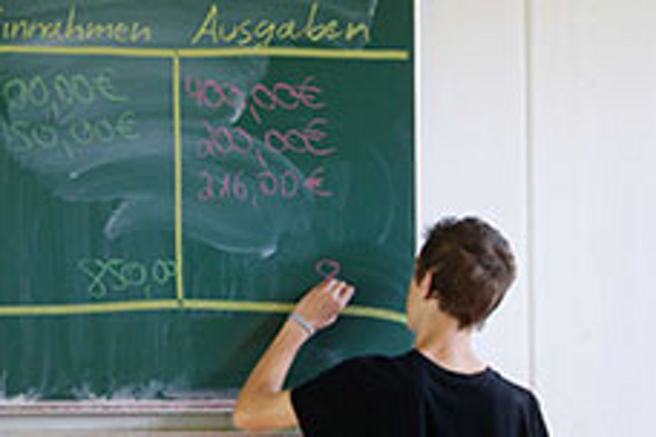 Ein Junge schreibt etwas an eine Schultafel.