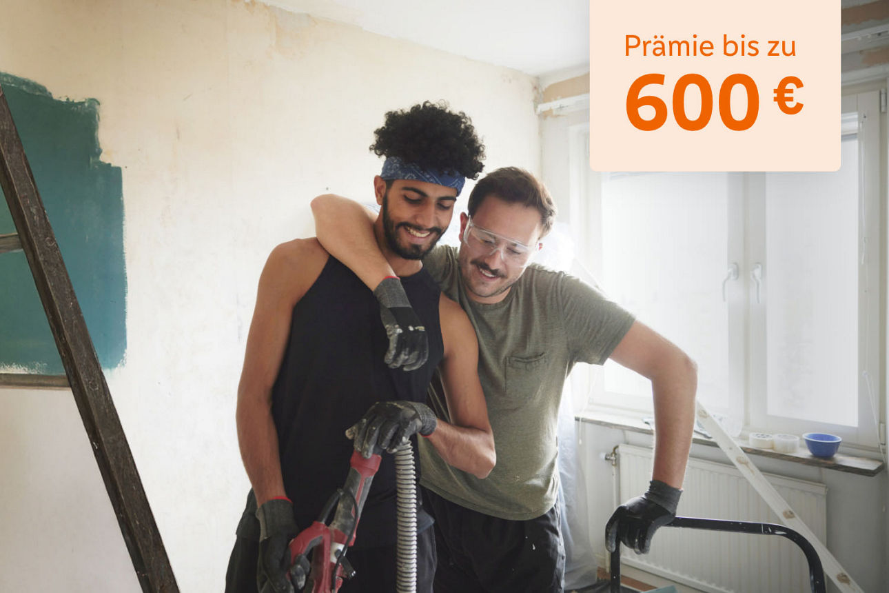Freunde beim Streichen im neuen Zuhause mit dem Hinweis "Prämie bis zu 600 €"