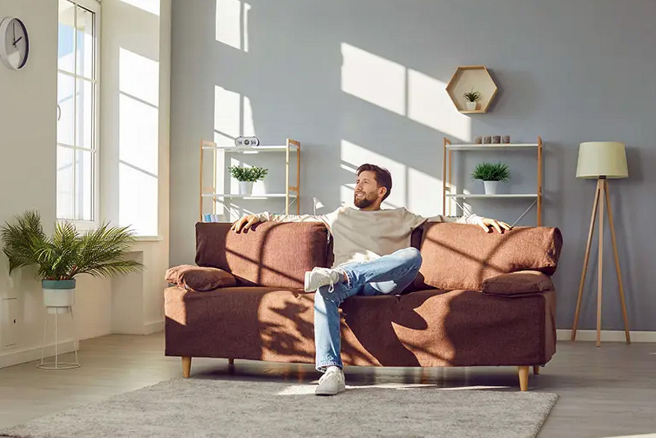 Junger Mann sitzt entspannt auf seiner Couch