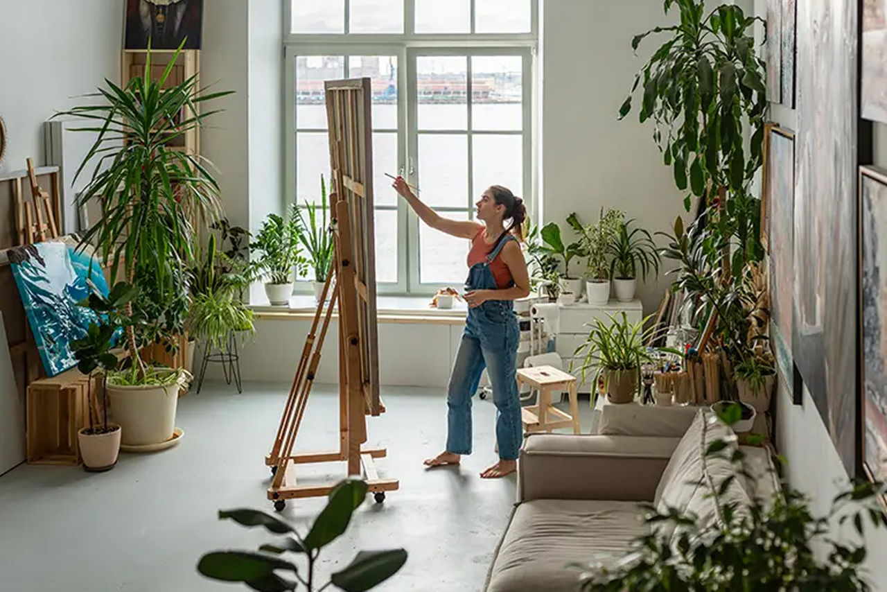 Junge Frau malt an einer Leinwand in ihrem Atelier Zuhause