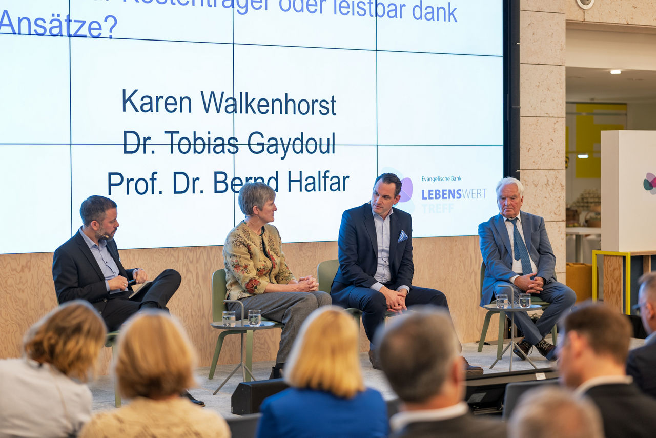 Vier Personen sitzen auf einer Bühne und diskutieren