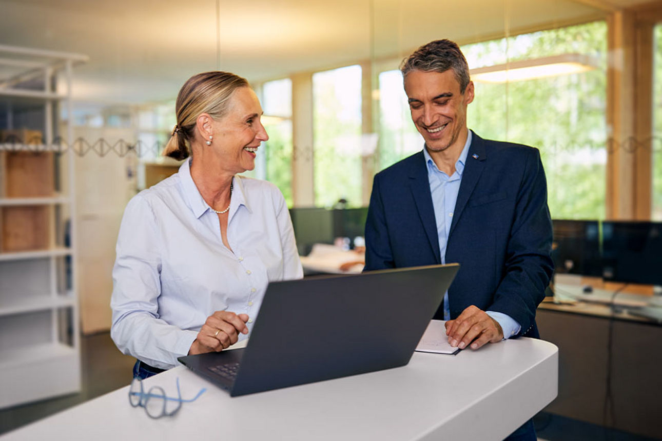Mann und Frau stehen an einem Laptop