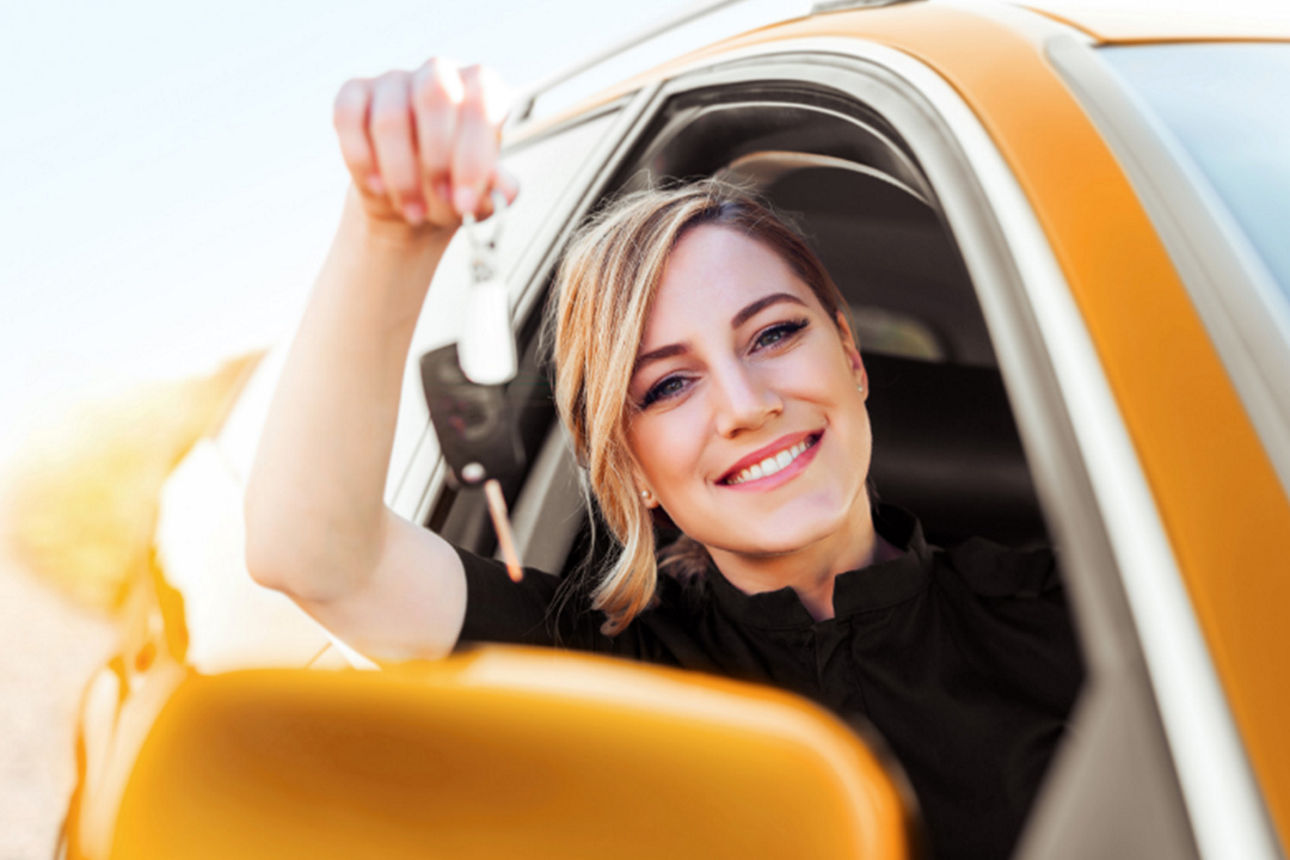 Junge Frau hält den Schlüssel ihres neuen Auto in der Hand