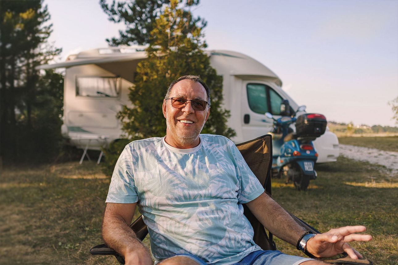 Mann sitzt entspannt im Campingstuhl vor seinem Wohnmobil