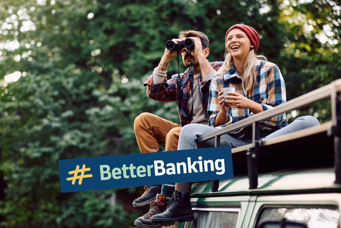 junges glückliches Paar sitzt auf Dach eines Campers, der Mann schaut durch ein Fernglas