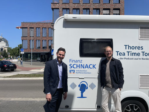 Zwei Männer stehen vor einem bedrucktem Wohnmobil.