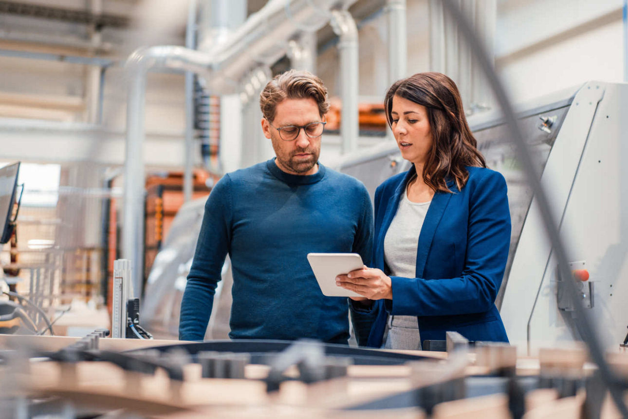 Mann und Frau stehen in einer Produktionshalle
