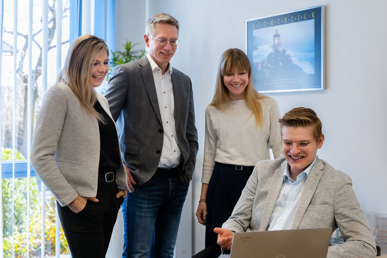 Zwei Männer und zwei Frauen vor einem Laptop