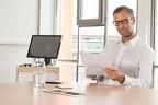 Mann im hellen Büro mit Papieren in der Hand