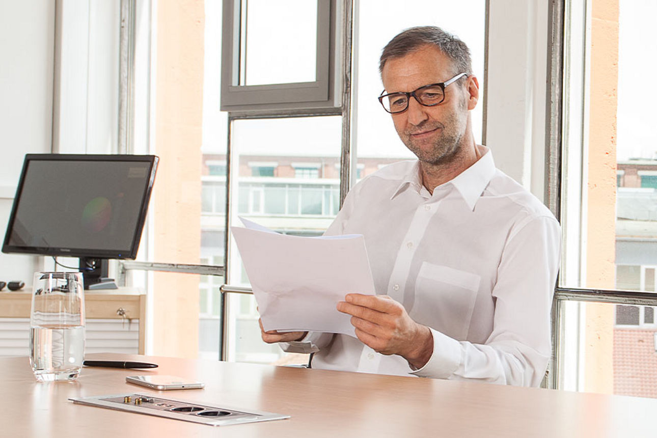 Mann im Büro und hält Dokumente in der Hand