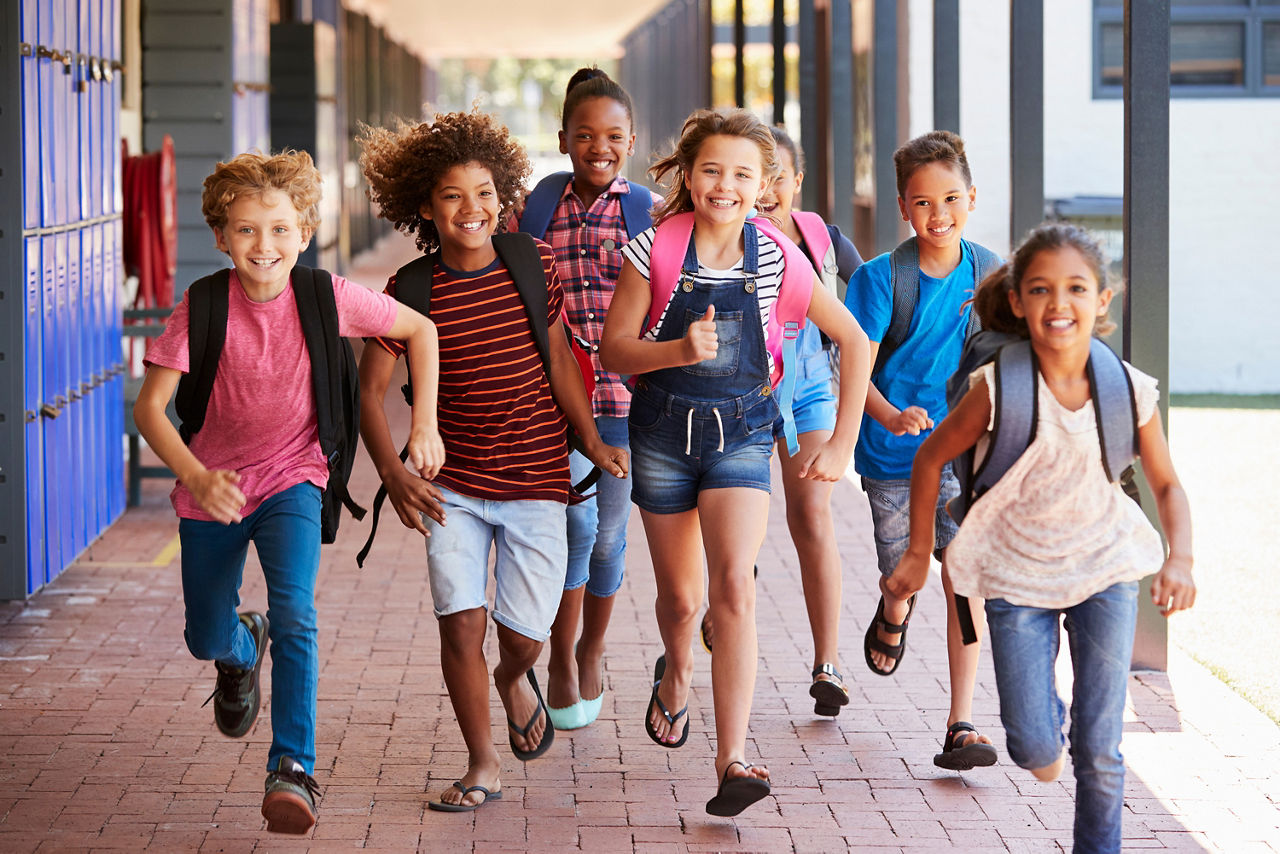 Eine Gruppe an Kindern rennt in einer Schule einen Gang entlang