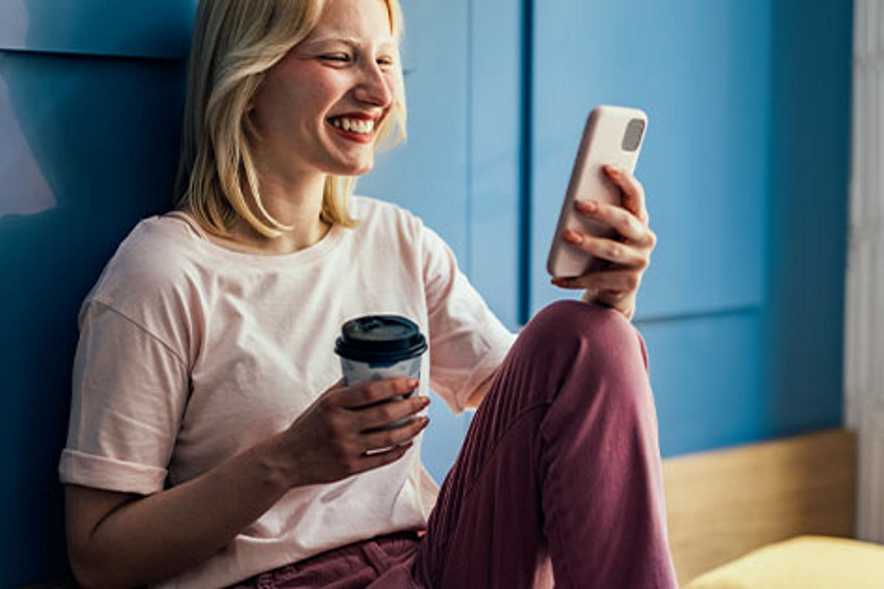 Junge Frau, die in die Kamera ihres Smartphones lächelt