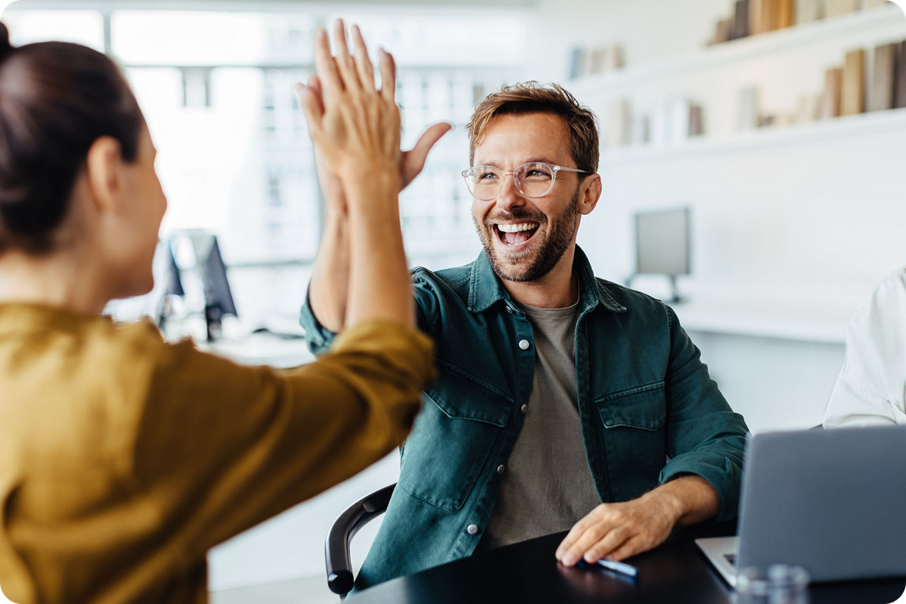 Eine Frau und ein Mann sitzen sich gegenüber und machen High Five