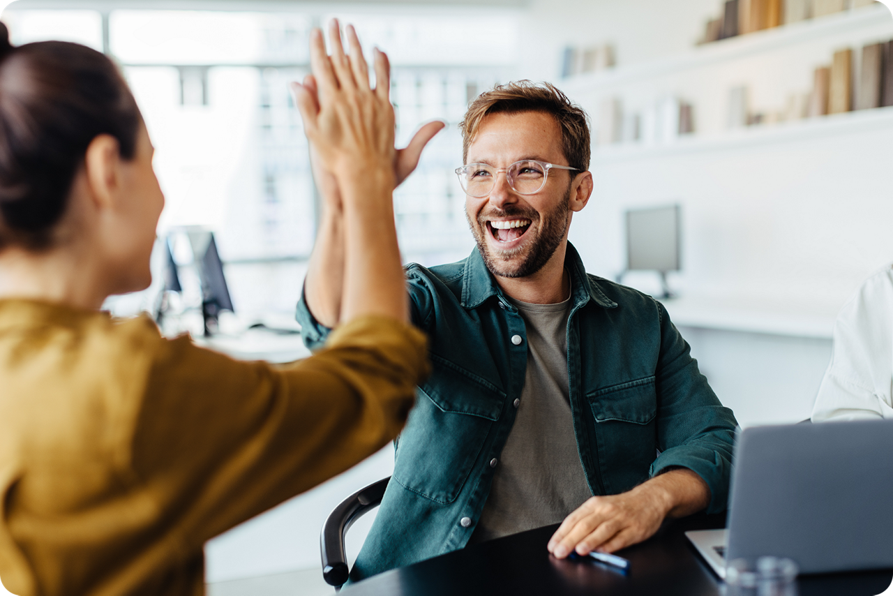 Eine Frau und ein Mann sitzen sich gegenüber und machen High Five