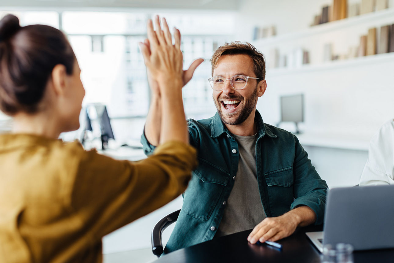 Eine Frau und ein Mann sitzen sich gegenüber und machen High Five