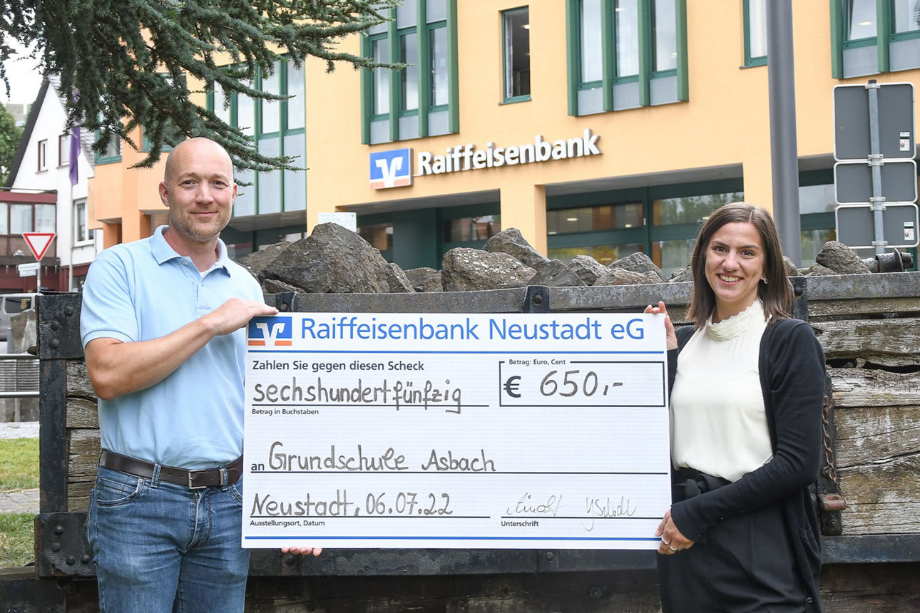 Sina Feldheiser übergibt einen Werbe-Spendenscheck an einen Lehrer der Grundschule Asbach