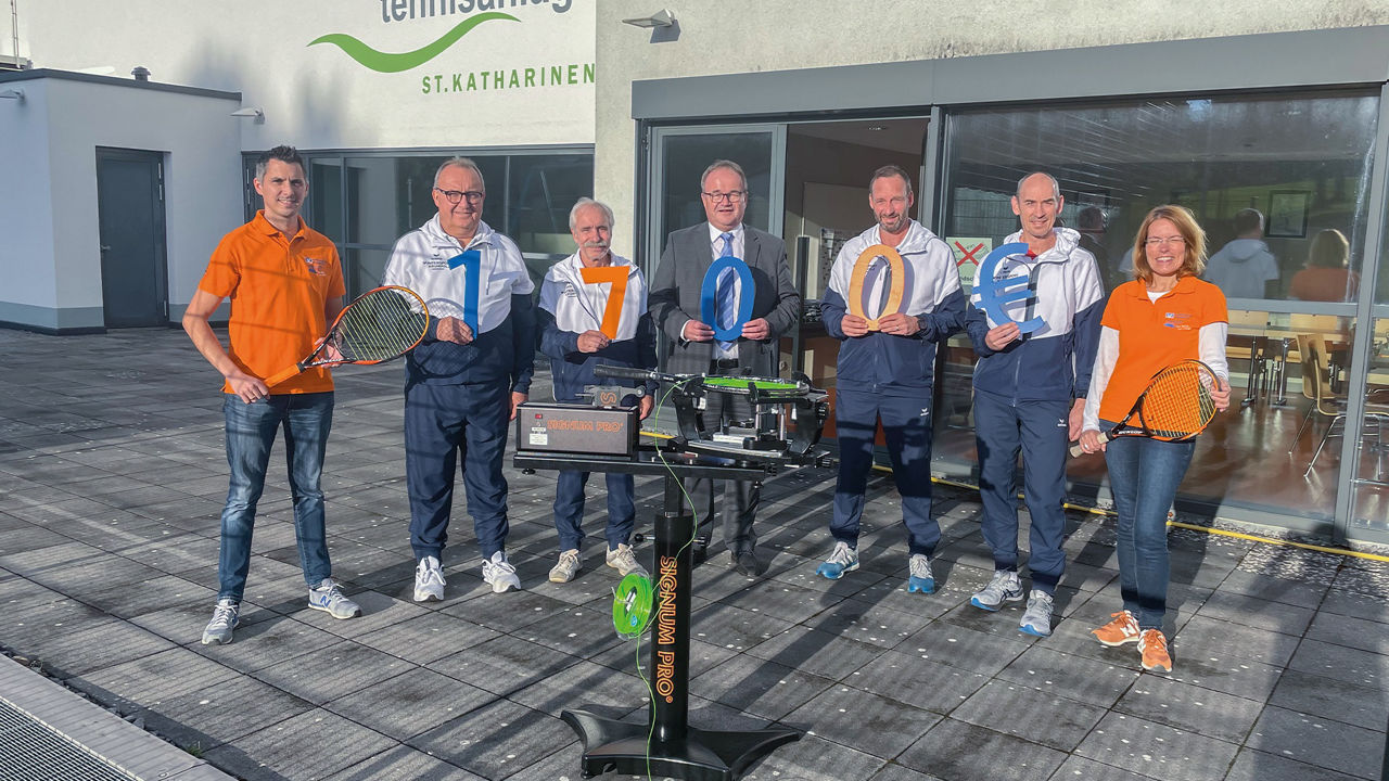 Ingo Stümper, Gabi Lahr und Martin Leis stehen mit Mitglieder der DJK St. Katharinen um die neue Besaitungsmaschine