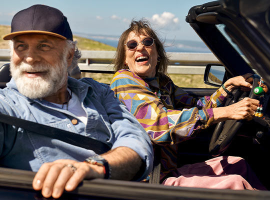 Mann und Frau sitzen lachend im Auto
