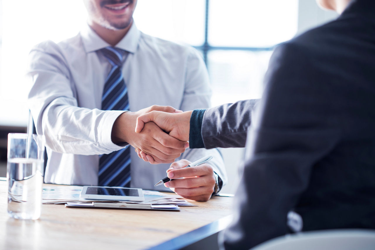 Zwei Businessmänner geben sich die Hand und einigen sich eine Versicherung abzuschließen