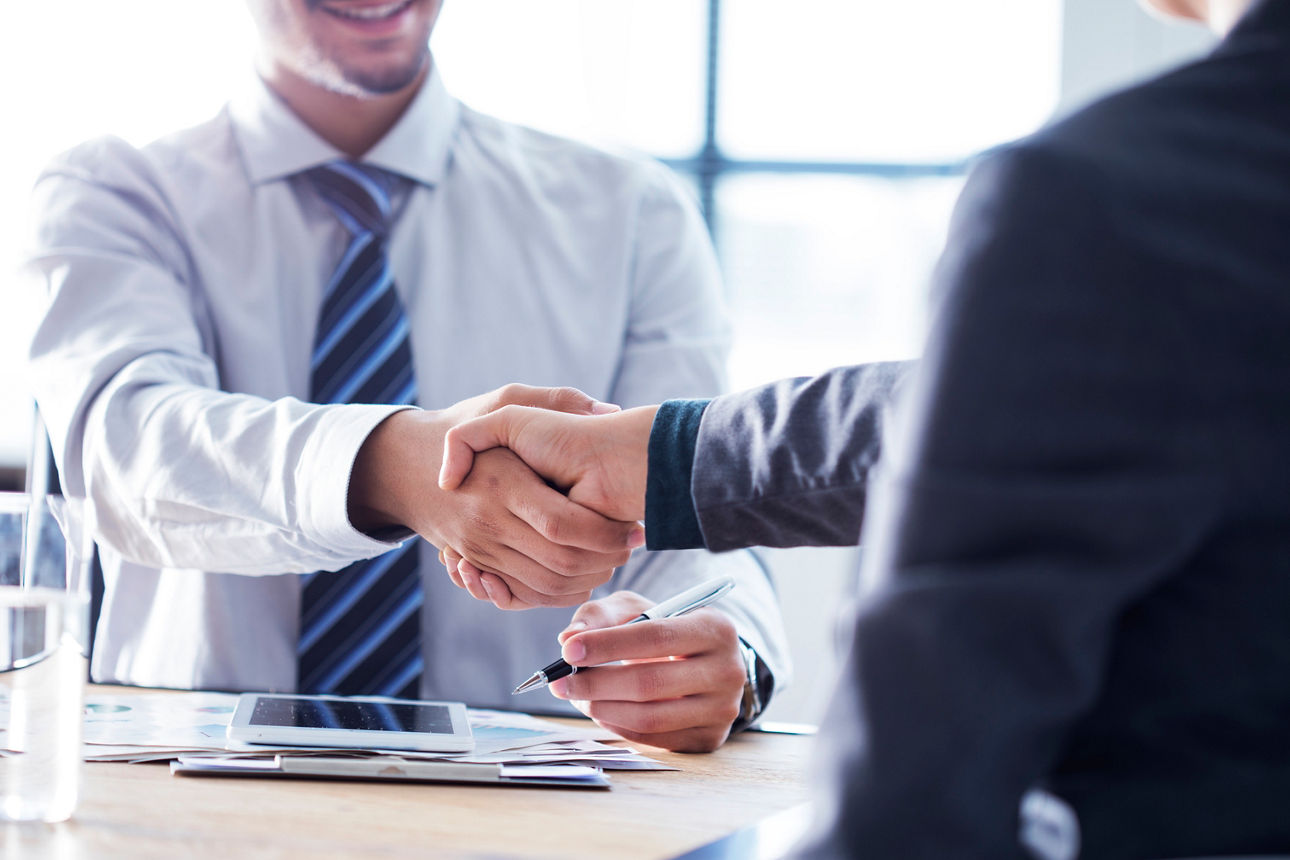 Zwei Businessmänner geben sich die Hand und einigen sich eine Versicherung abzuschließen
