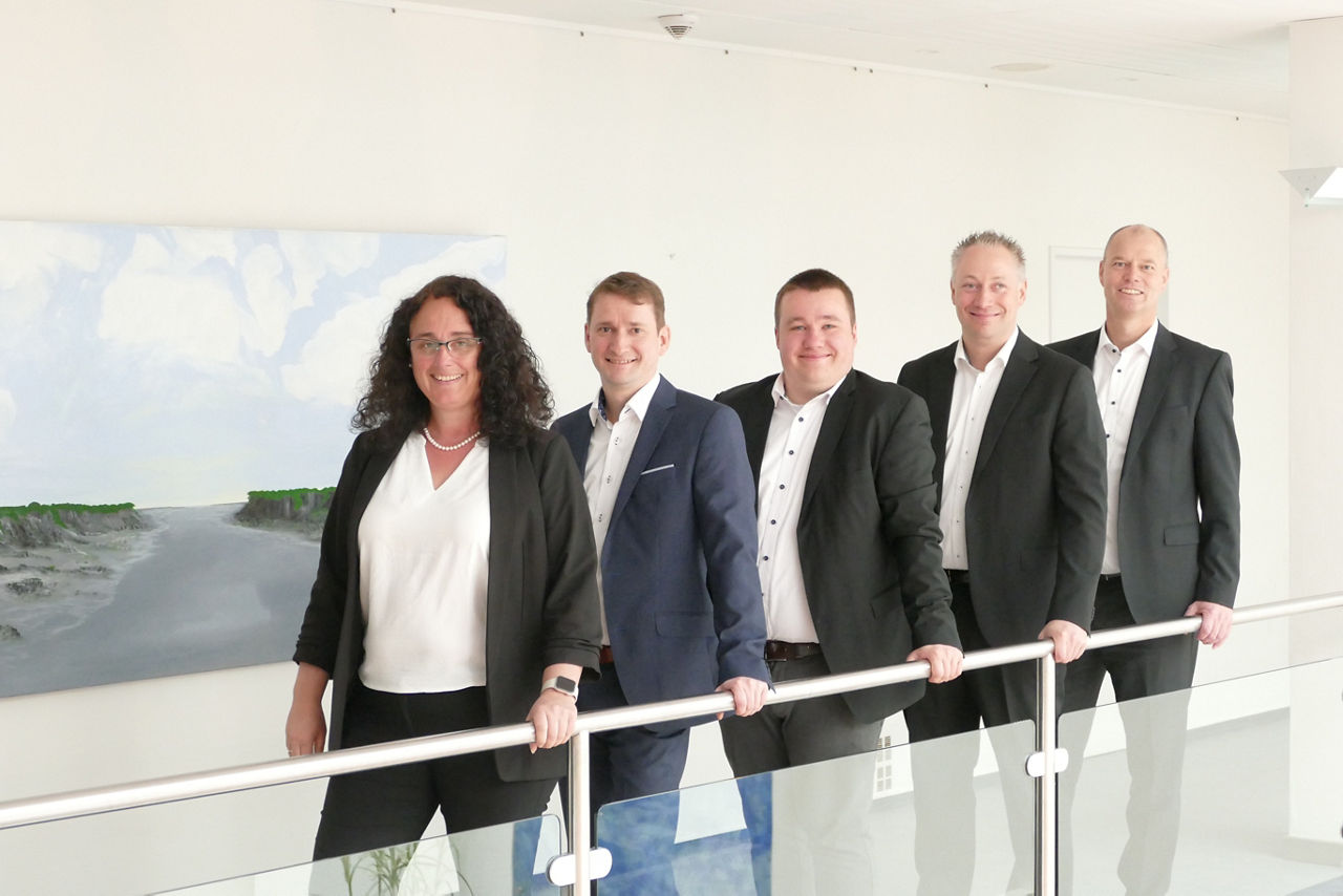 Das Team der Firmenkundenberatung der DVRB steht lächelnd in der Hauptstelle Heide
