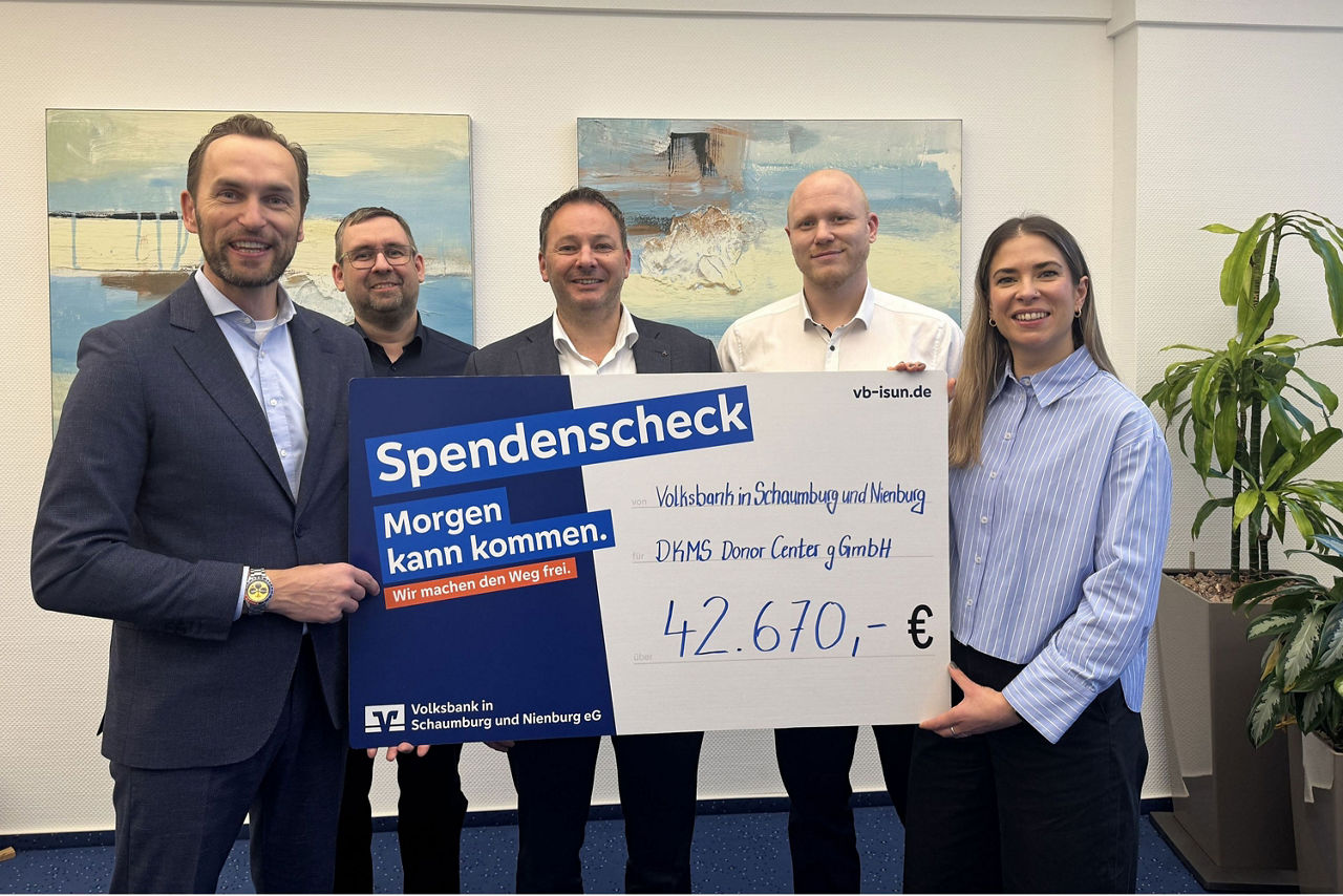 Fünf Personen in Businesskleidung halten einen exemplarischen Scheck hoch