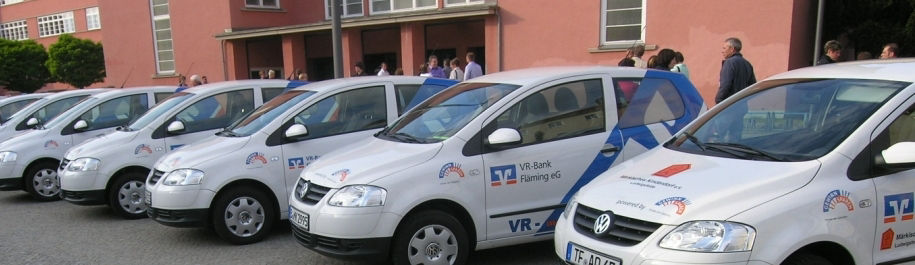 Eine Reihe weißer und blauer Autos, die ordentlich vor einem modernen Gebäude geparkt sind und ein lebendiges Stadtbild zeige