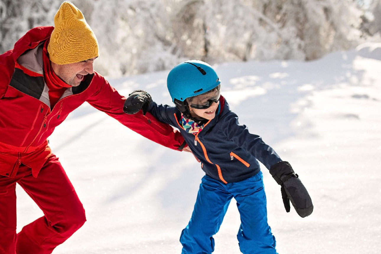 Vater lernt mit seinem Kind Snowboard fahren