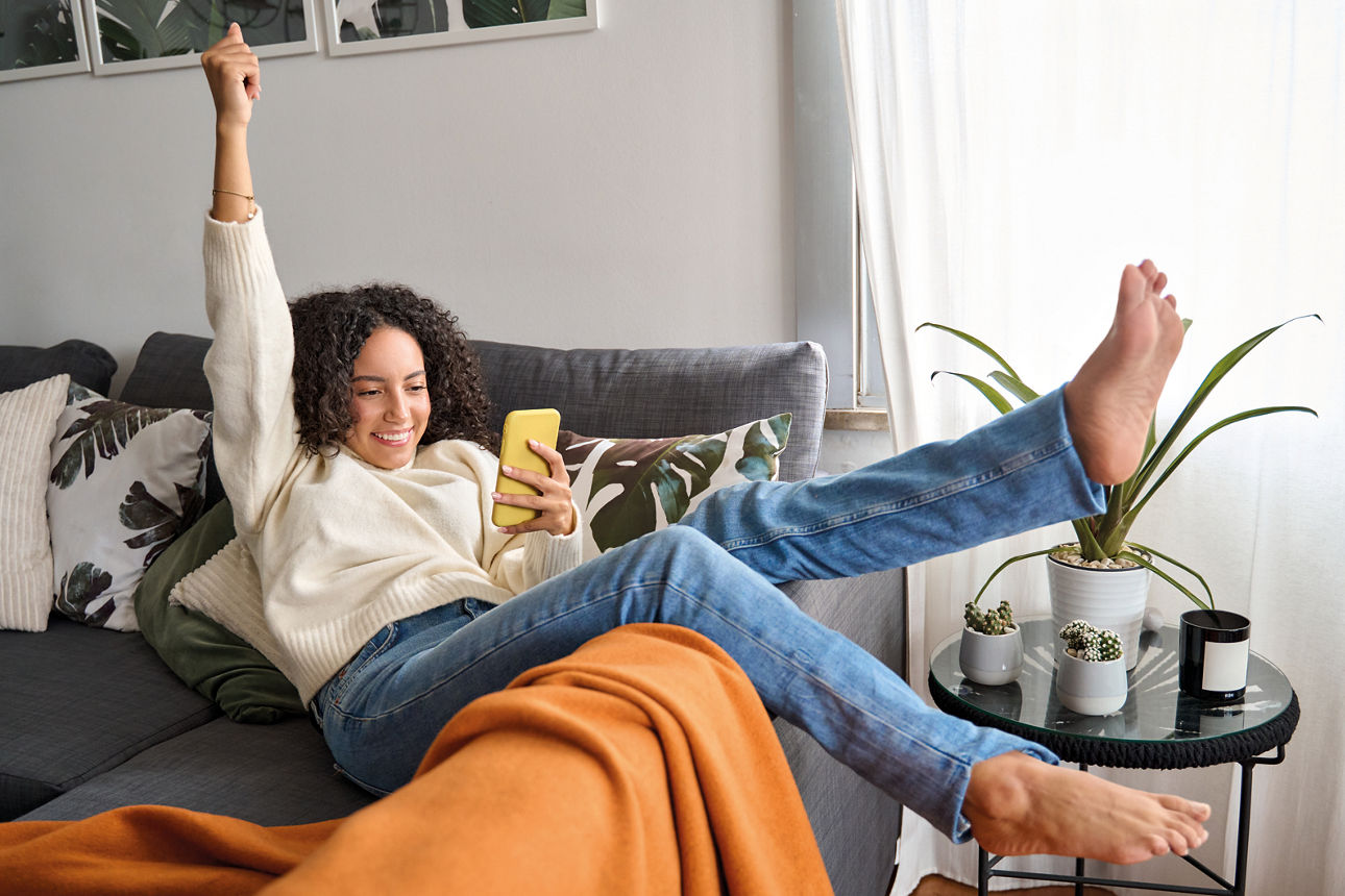 frau sitzt auf dem sofa und ist am handy