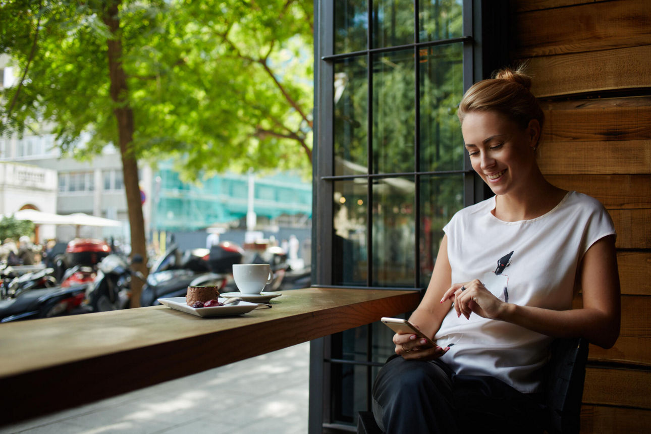 Frau mit Smartphone im Café am Fenster