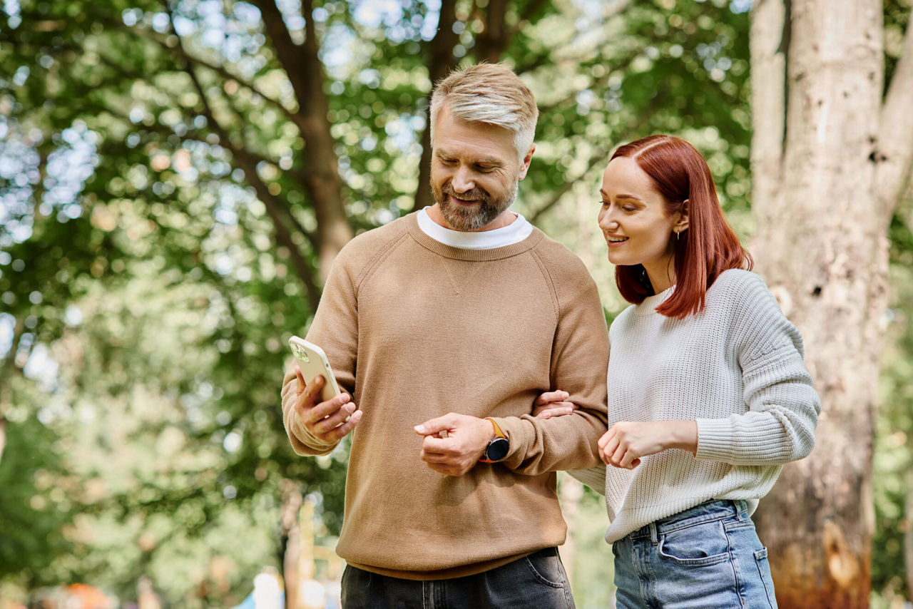 Mann und Frau in der Natur auf Smartphone schauend.