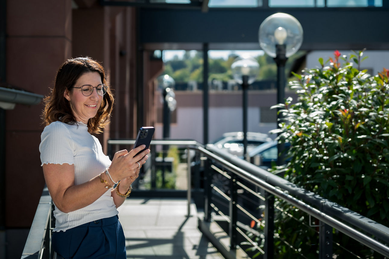 Eine Frau steht draußen mit einem Handy in der Hand