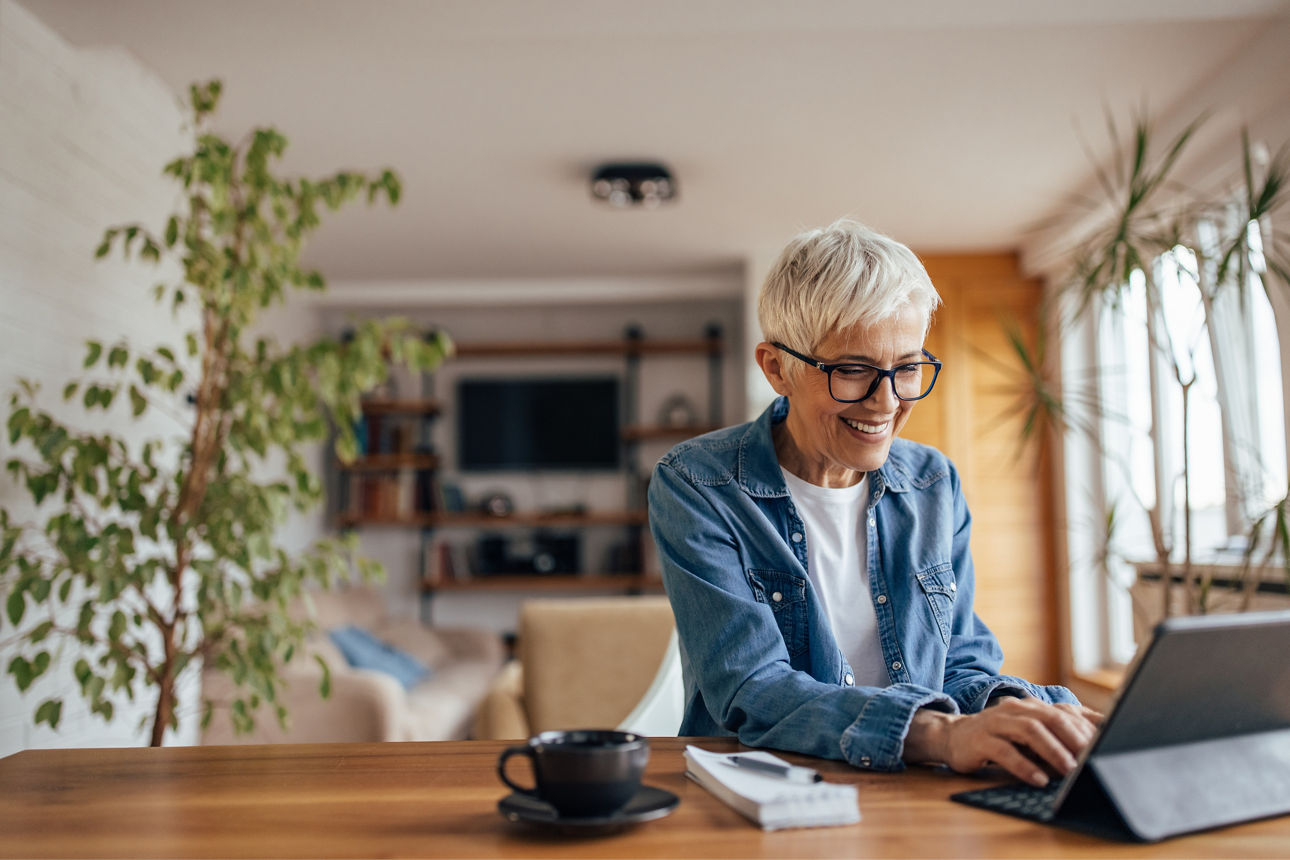 Mature woman, checking her bank account online, while drinking coffee.