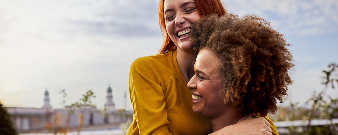 Zwei Frauen auf einer Dachterrasse, die sich umarmen.
