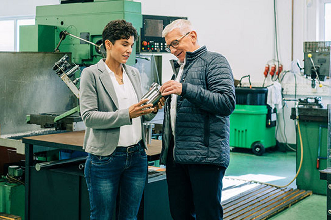 Geschäftsführerin und Mitarbeiter in einer Fabrikhalle