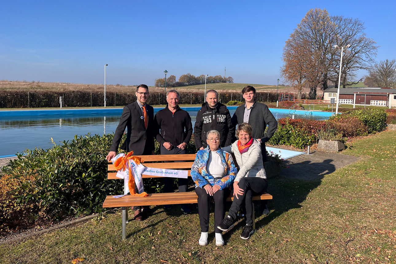 Sechs Personen stehen um eine Holzbank, die im Freibad Großnaundorf aufgestellt ist. 