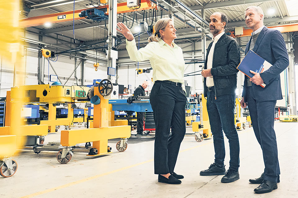 Drei Geschäftsleute stehen in einer Fabrikhalle