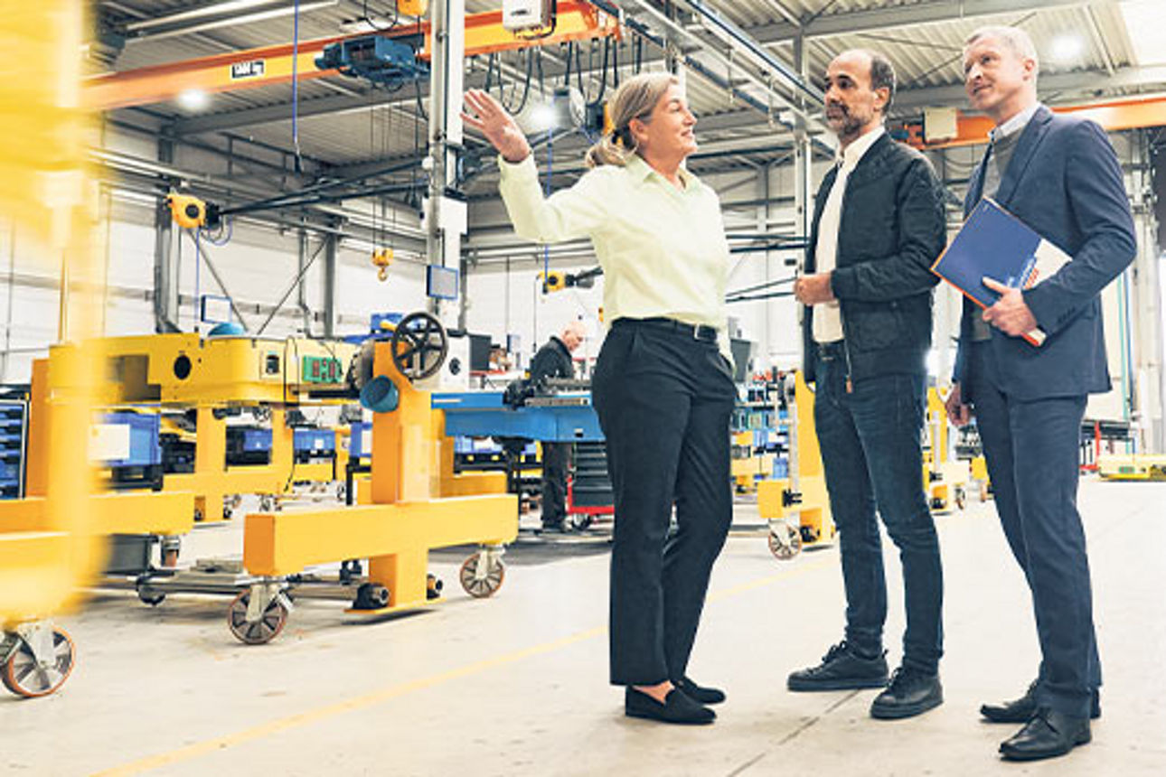 Drei Geschäftsleute stehen in einer Fabrikhalle