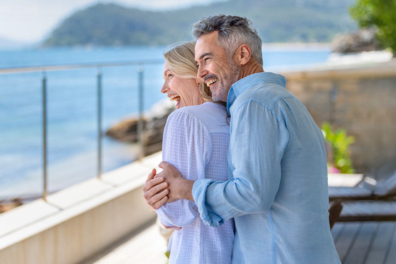 Älteres Paar auf einer Terrasse blickt auf das Meer