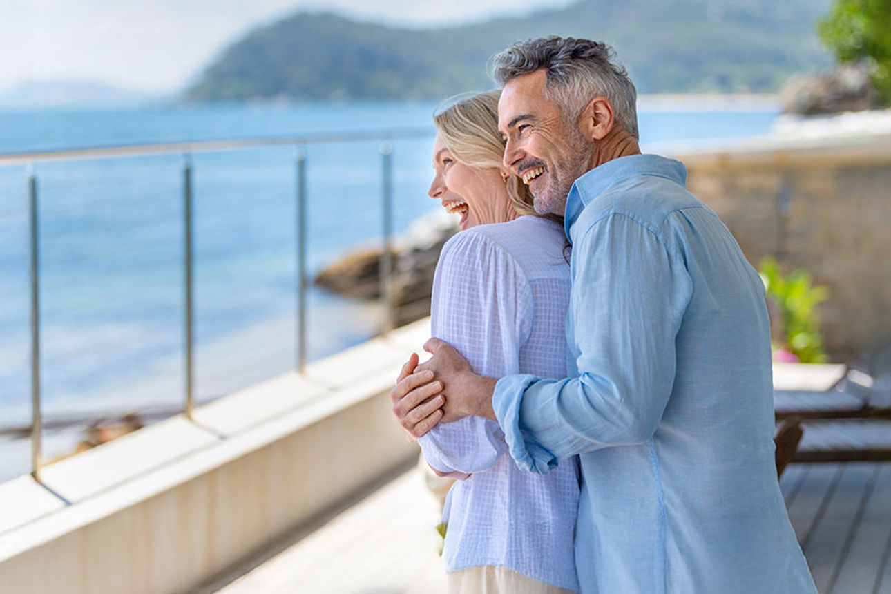 Älteres Paar auf einer Terrasse blickt auf das Meer
