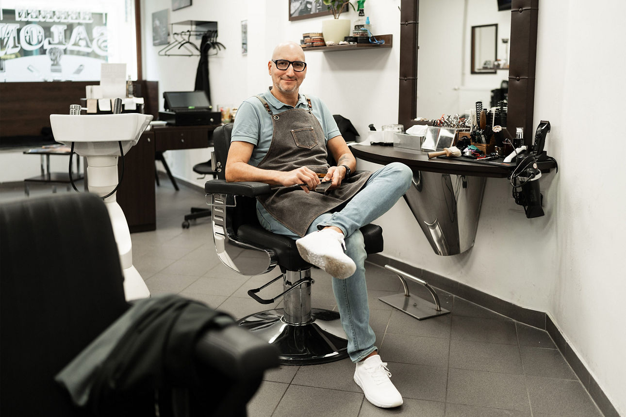 Ein Mann mit Glatze sitzt in einem Friseurstuhl