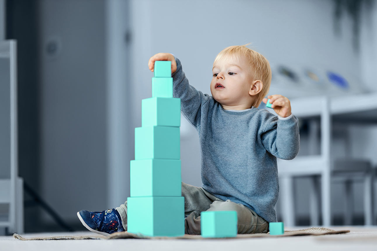 Kleines Kind spielt mit hellblauen Bauklötzen.