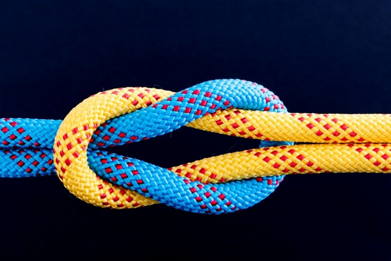 Ein blaues und ein oranges Seil durch einen Kreuzknoten verbunden