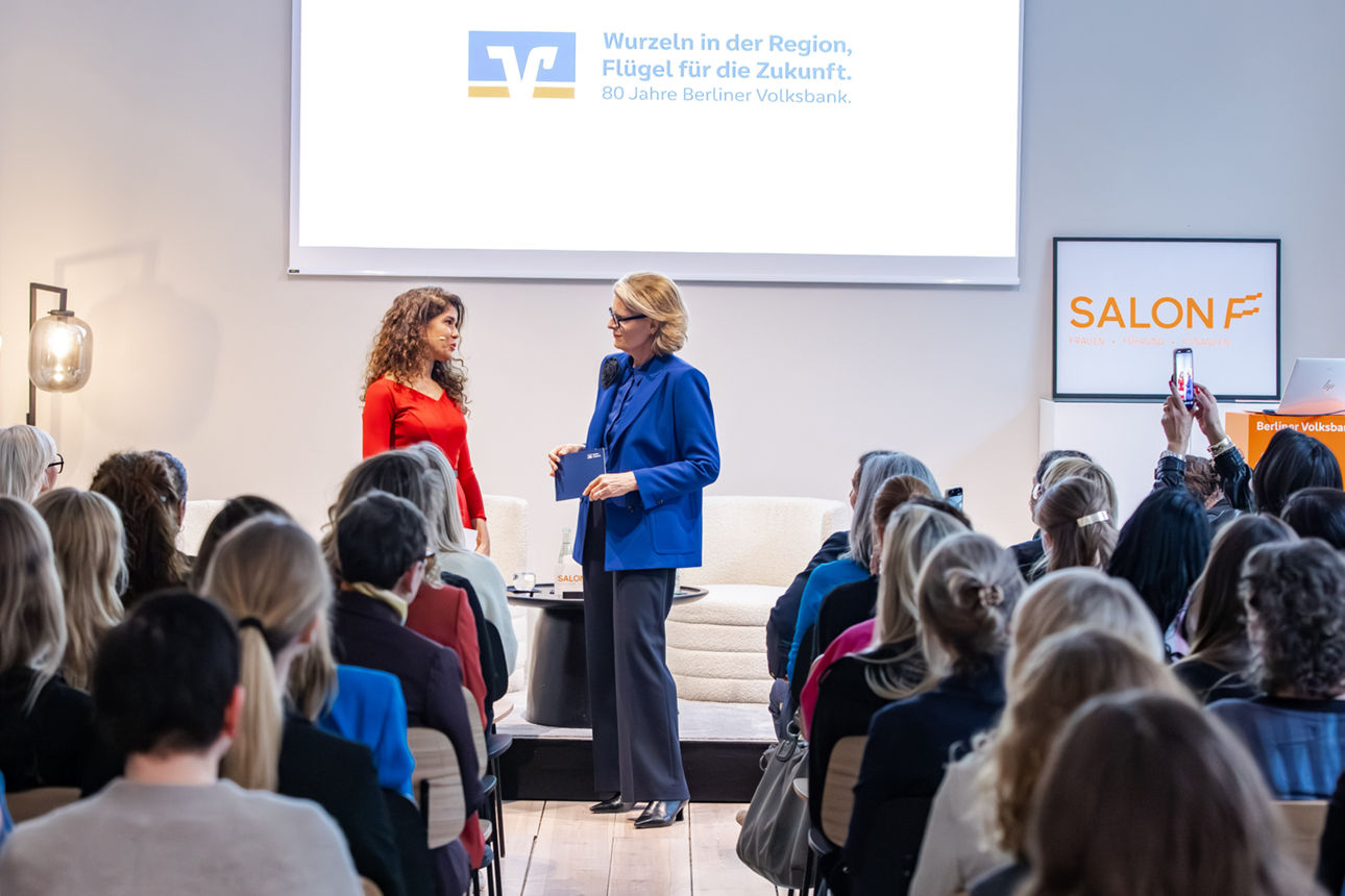 Zwei Frauen stehen auf der Bühne und das Publikum schaut sie an