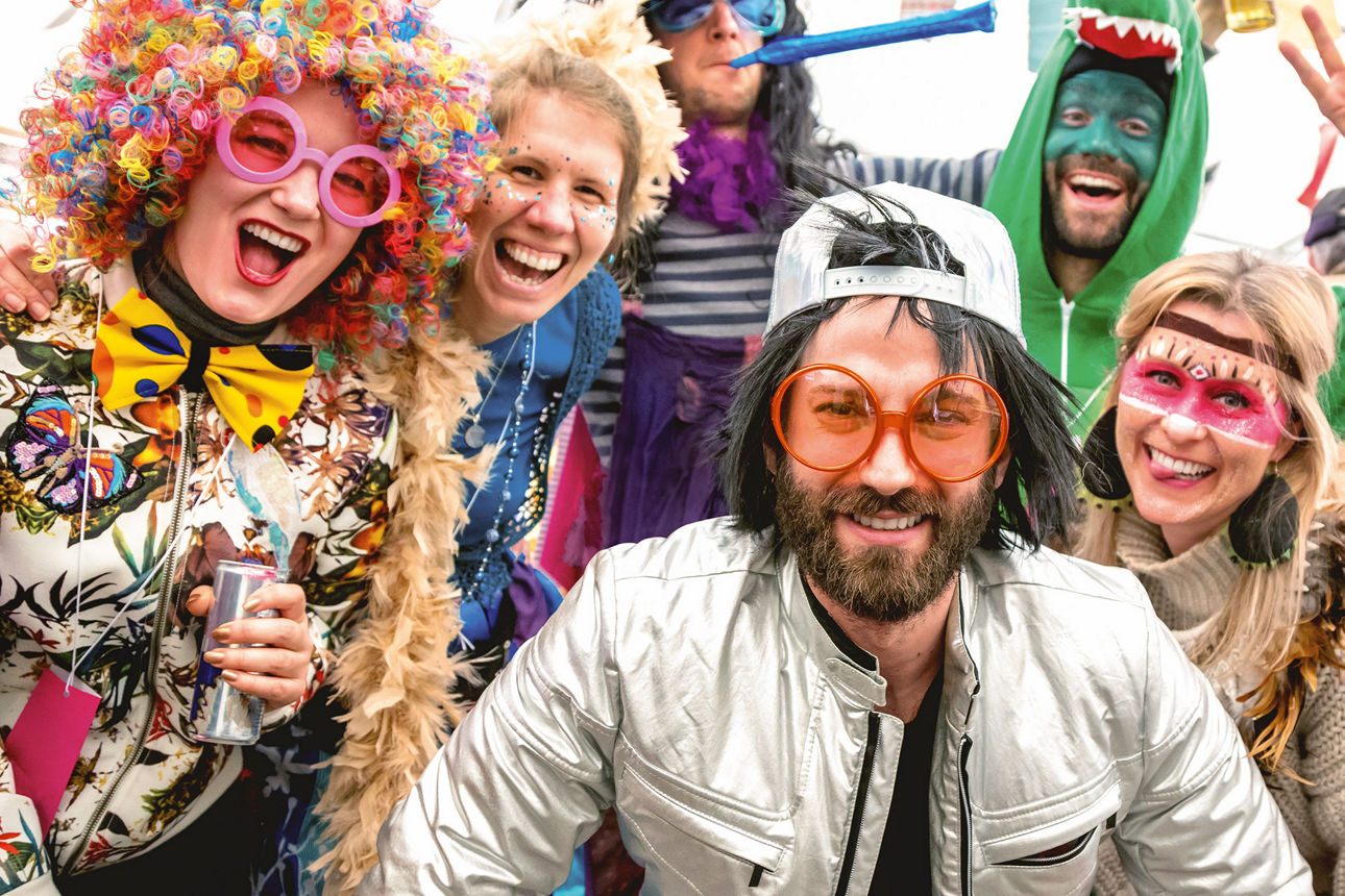 Eine Menschengruppe in Faschingskostümen lachen in die Kamera.