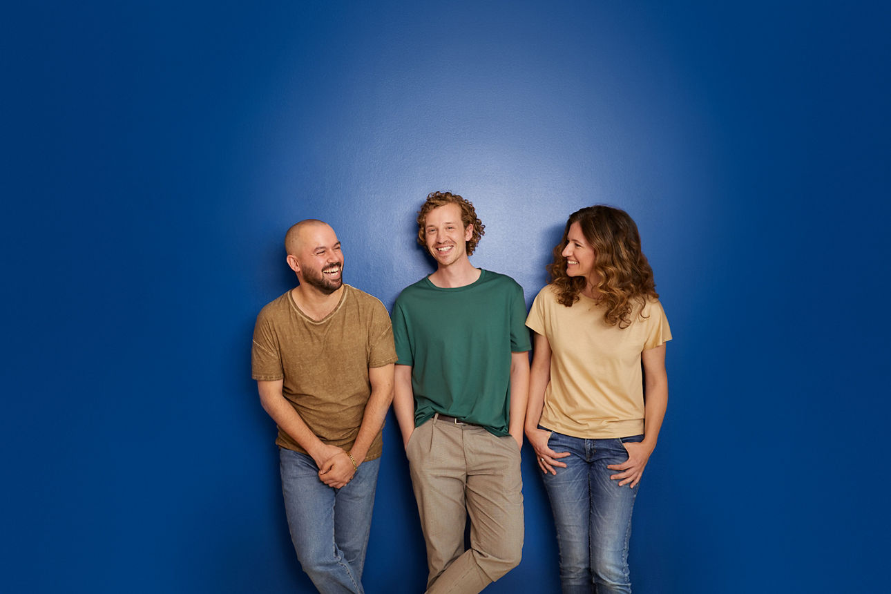 zwei Männer und eine Frau vor einem blauen Hintergrund