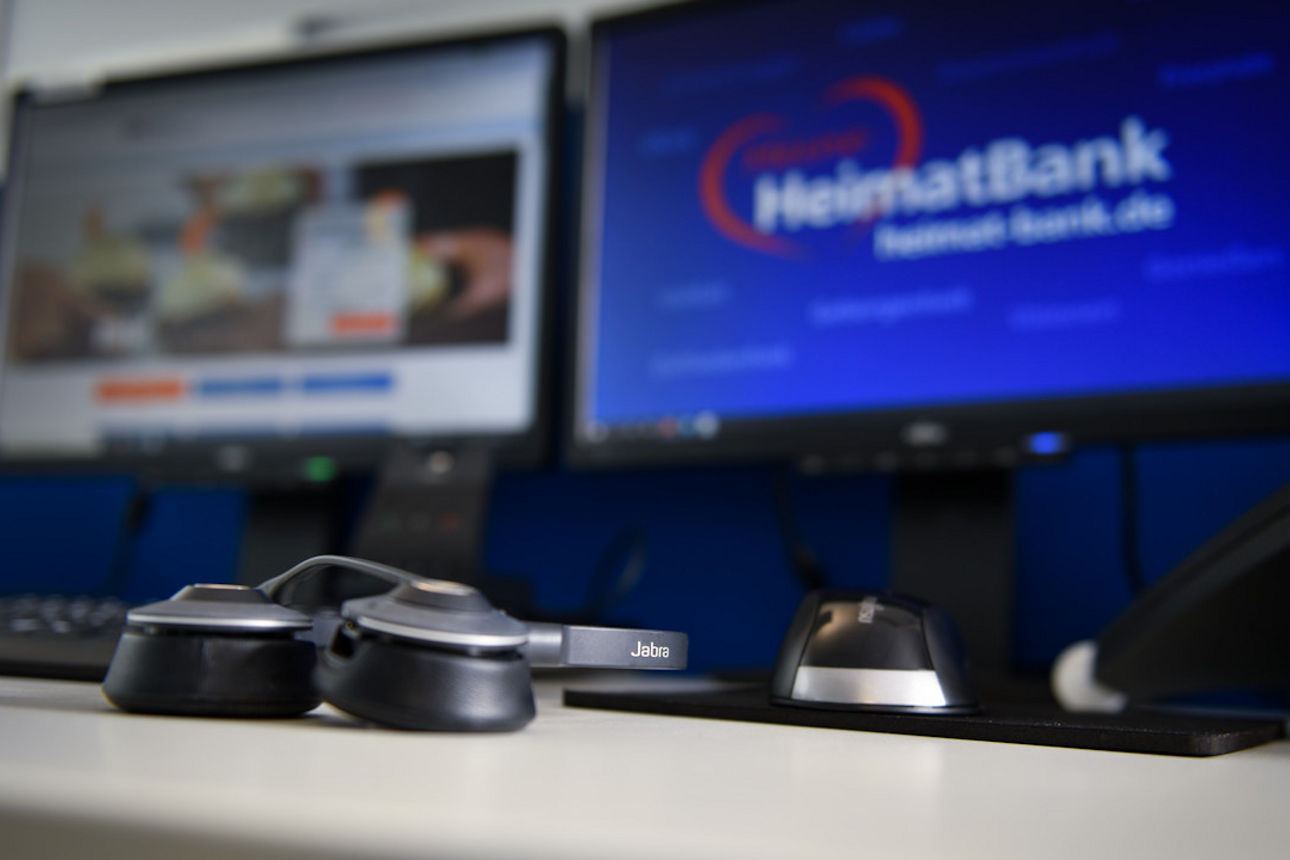 Monitore und ein davor liegendes Headset